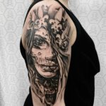 Oberarmtattoo mit düsterer Frau als Motiv in schwarzer Farbe