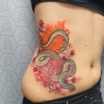 Schlange im Blumenmeer Tattoo an der Hüfte