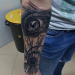 Unterarm Tattoo mit einem gemischten Motiv aus einem Auge und einer Wendeltreppe im Stile einer Uhr