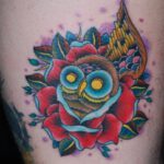 Eine Eule mit gelben Augen in einer Rose als Tattoo