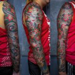 Volles Arm Tattoo mit Blüten auf schwarzem Grund