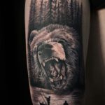 Tattoo mit Waldmotiv aus dem ein wütender Bär herausragt